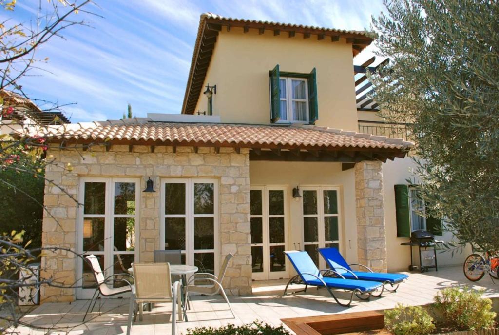 uma pequena casa com cadeiras e um pátio em Villa Nefeli - charming townhouse in the heart of Aphrodite Hills Resort em Kouklia