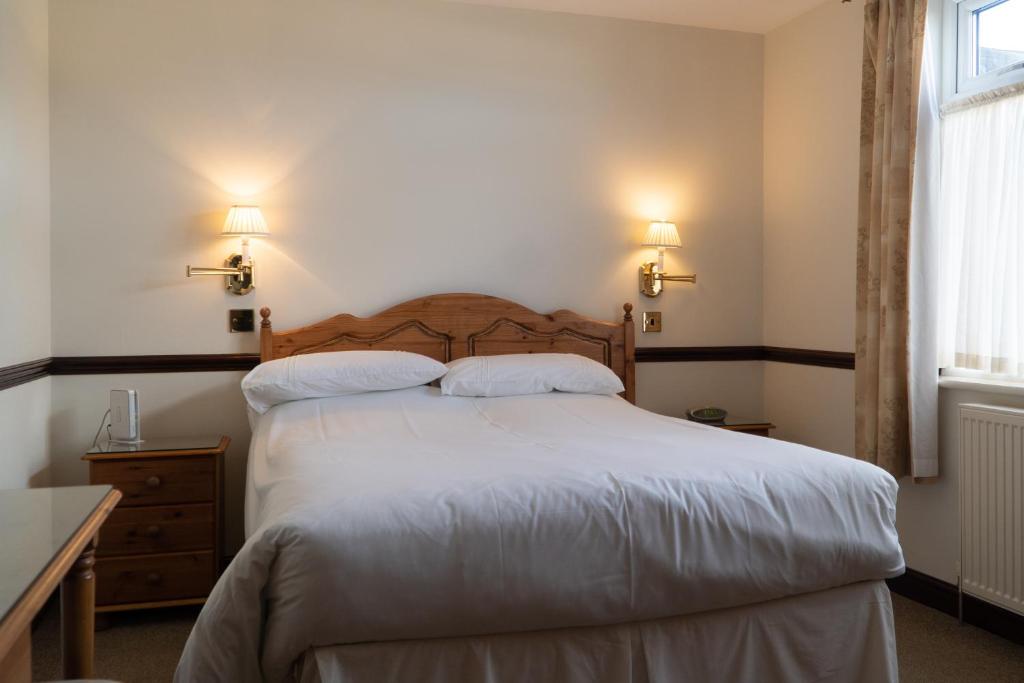 a bedroom with a bed with white sheets and two pillows at The Olde Ship Inn in Seahouses