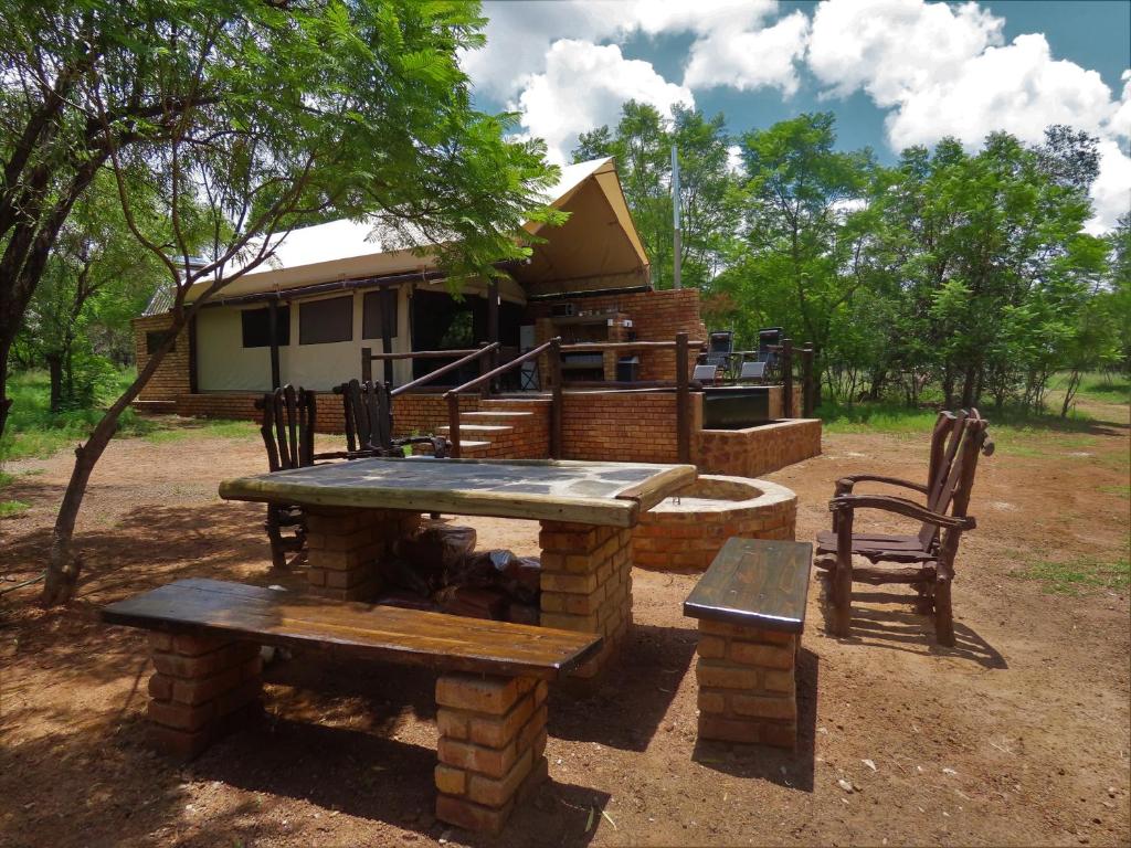 a picnic table and bench in front of a house at Beka Idube Bushveld Retreat in Cullinan