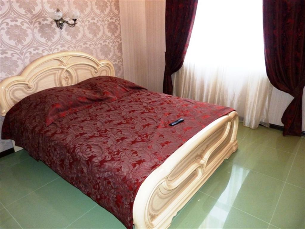 a bedroom with a bed with a red blanket and a window at Hotel Eliziy in Aramil'