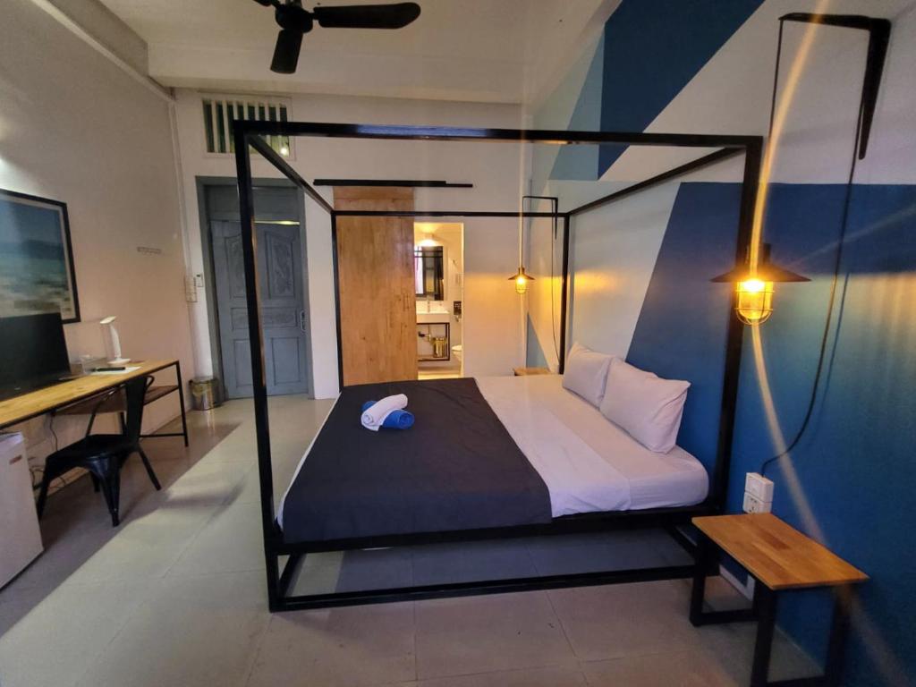 Dormitorio con cama con dosel, escritorio y TV en THE PLACE Hostel & Rooftop Bar en Battambang