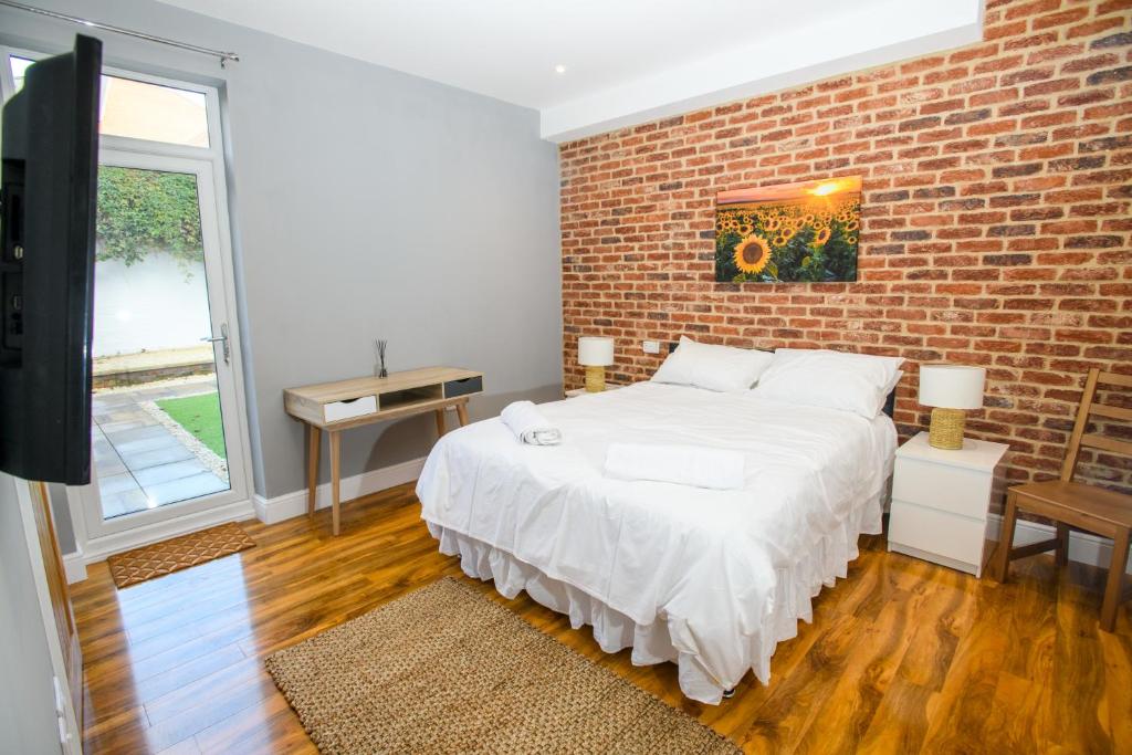 a bedroom with a white bed and a brick wall at Tavmar Rooms in Lincoln
