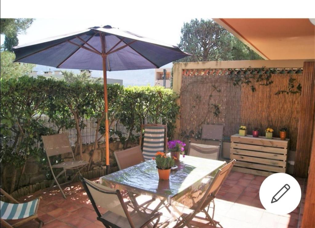 un patio avec une table et un parasol dans l'établissement Appartement avec jardin, à Cassis