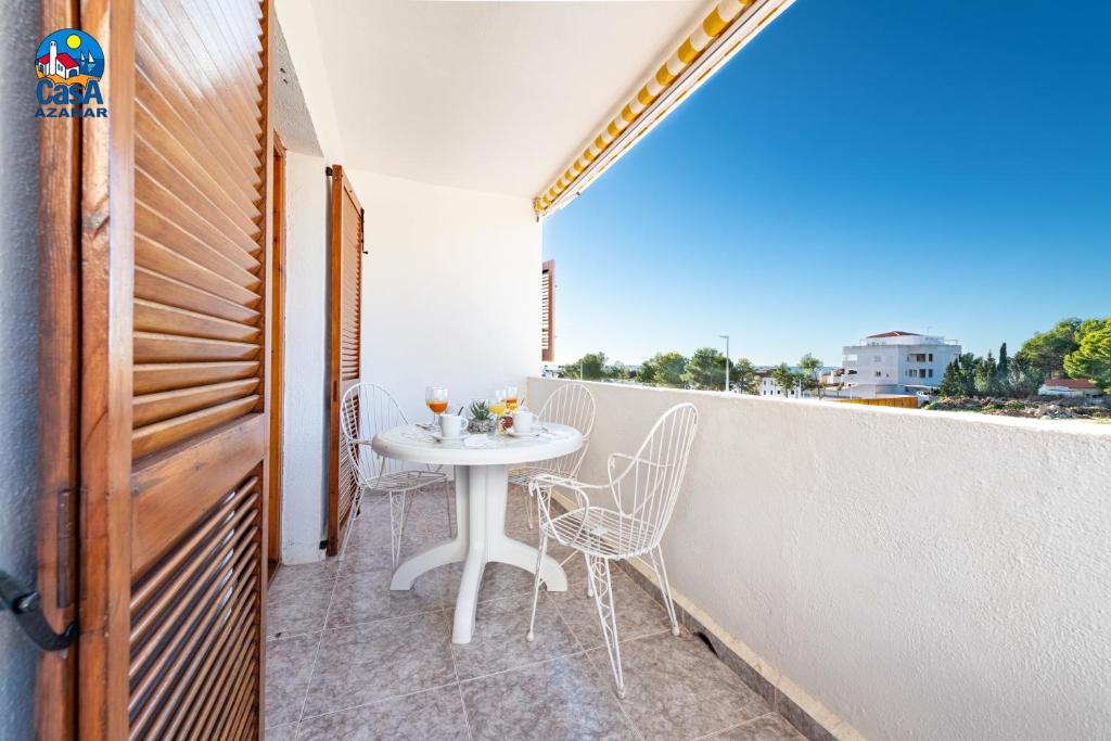 - Balcón con mesa blanca y sillas en Apartamentos Hibiscus Casa Azahar, en Alcossebre