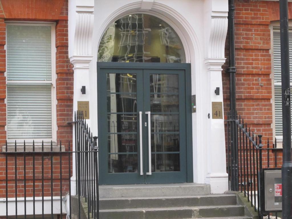 - une porte bleue dans un bâtiment en briques avec des escaliers dans l'établissement BLOOMSBURY APARTMENTS, à Londres