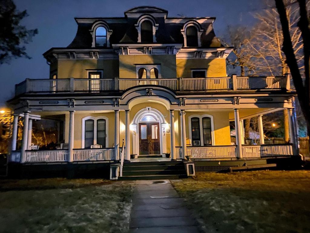 una casa vieja por la noche con las luces encendidas en Mini Mansion Hotel affordable stays Plainfield NJ near public transportation, en Plainfield