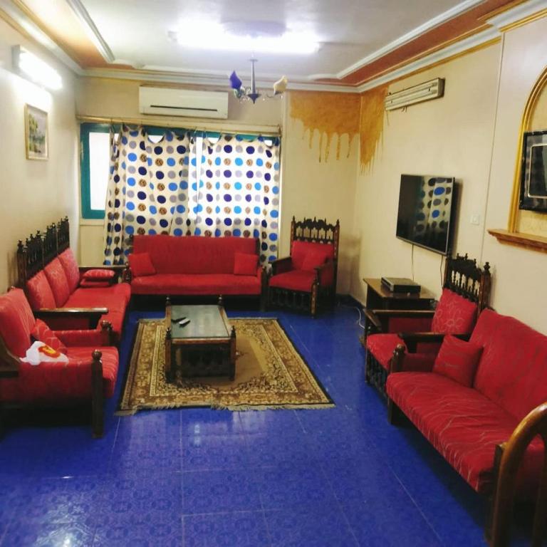 ein Wohnzimmer mit roten Sofas und einem TV in der Unterkunft Elredy's apartments the blue edition in Kairo