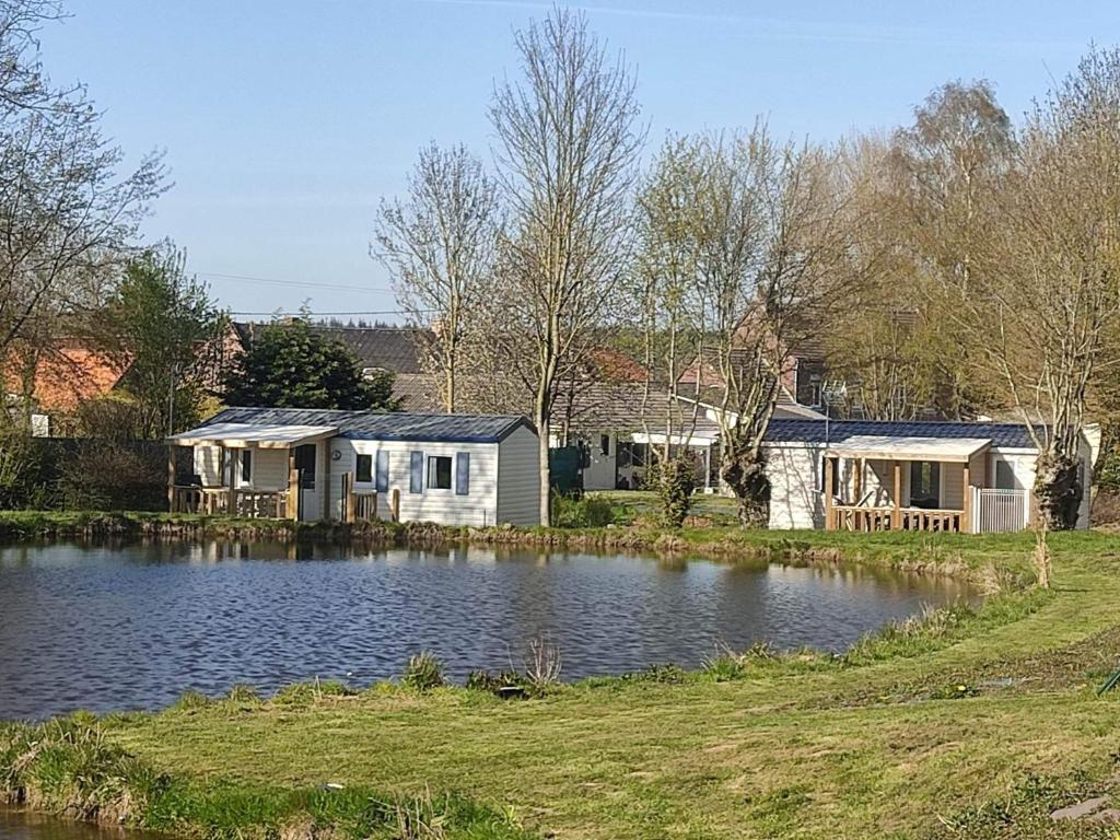 une maison avec un étang en face de celle-ci dans l'établissement Camping Les Sources Liencourt, à Liencourt