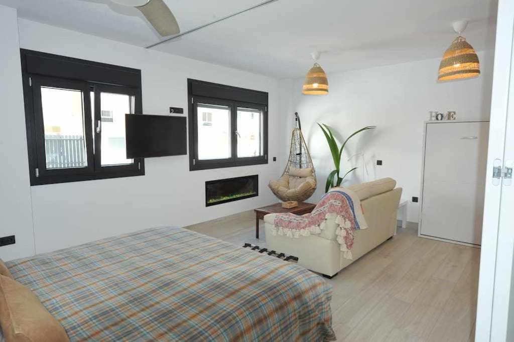 een slaapkamer met een bed, een bank en ramen bij Acogedor apartamento en la playa de Cádiz in Cádiz