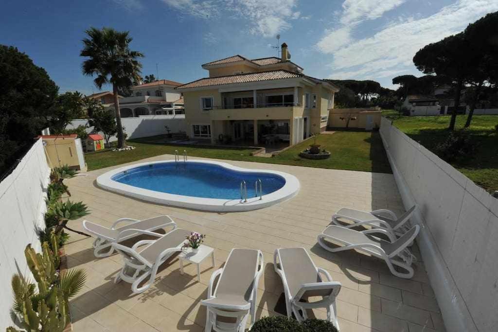 una piscina con tumbonas y una casa en Chalet Villa Ventolera Novo Sancti Petri Chiclana, en Chiclana de la Frontera