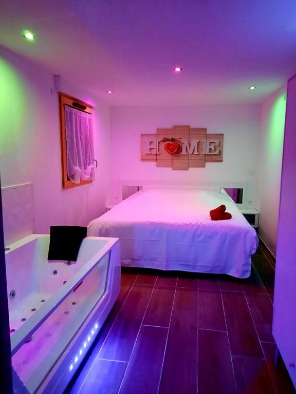 - une chambre avec un lit et une baignoire à éclairage violet dans l'établissement Votre studio balnéo bien-être à la montagne, à Thollon-les-Mémises