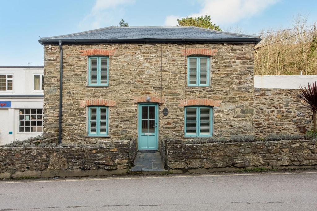 an old stone building with a blue door at Beach Cottage in St. Agnes