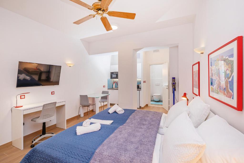 a white bedroom with a blue bed and a desk at Stylish studio Dare next to the City walls in Dubrovnik