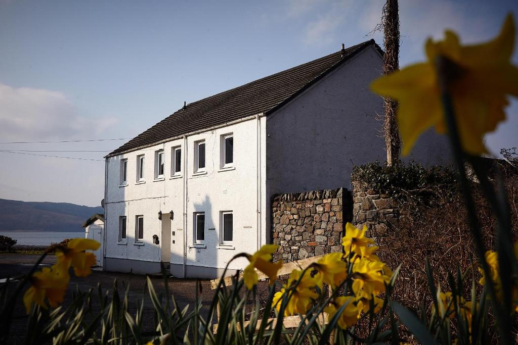 un edificio bianco con fiori gialli di fronte di Hidden Gem in a great location very near Isle of Skye a Kyle of Lochalsh