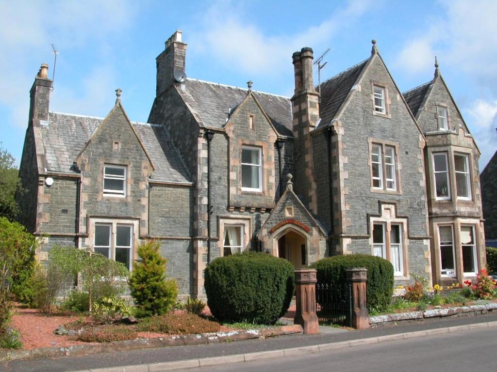 an old gray brick house with bushes in front of it at Hartfell Guest House in Moffat