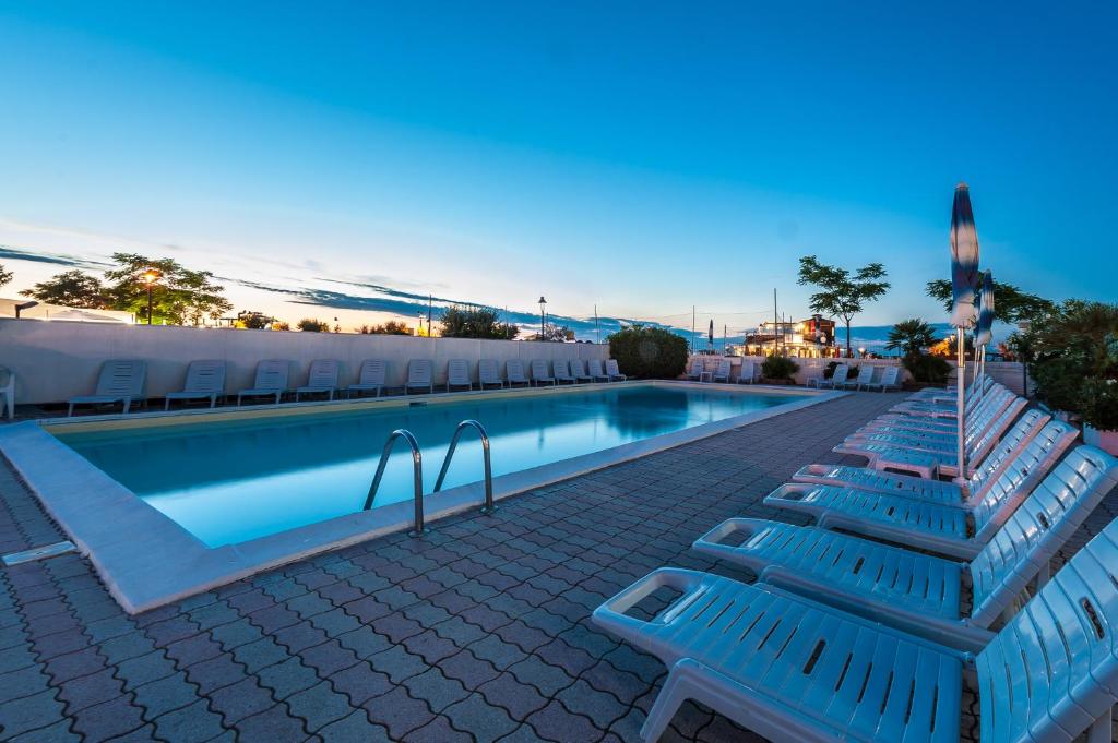 basen z 2 niebieskimi ławkami obok niego w obiekcie Hotel Corinna w Rimini