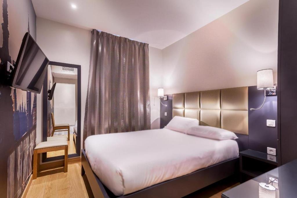 パリにあるオテル ジェナーのベッドとテレビが備わるホテルルームです。