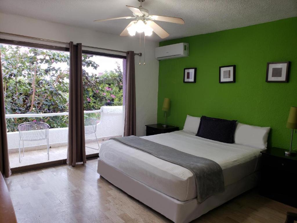 1 dormitorio con cama y pared verde en Hotel Green 16, en Cancún