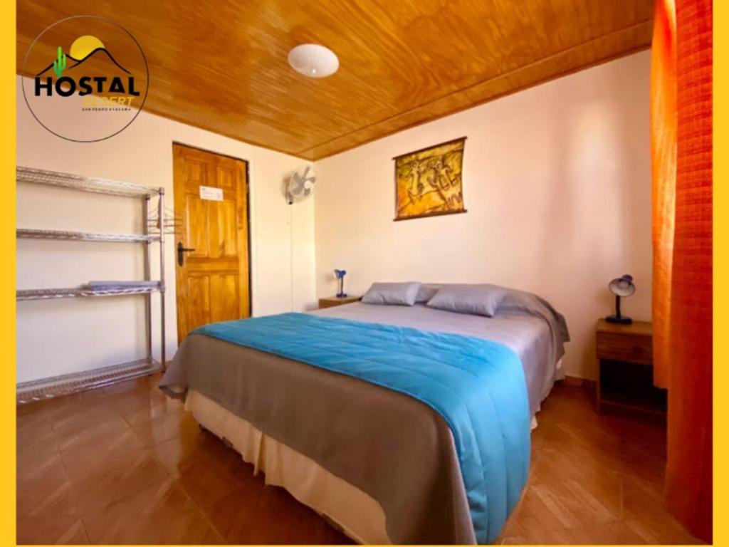 a bedroom with a bed with a blue blanket at Hostal Desert in San Pedro de Atacama