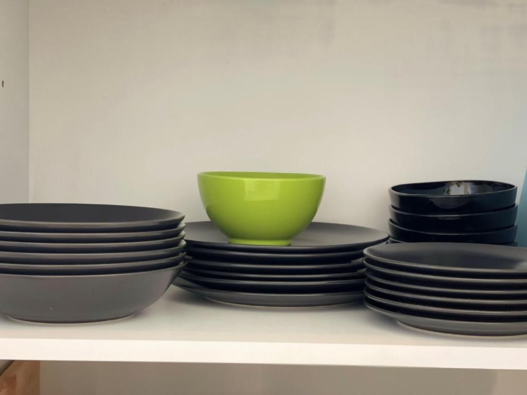 a stack of plates and bowls on a shelf at Robert's White Apartament in Ploieşti