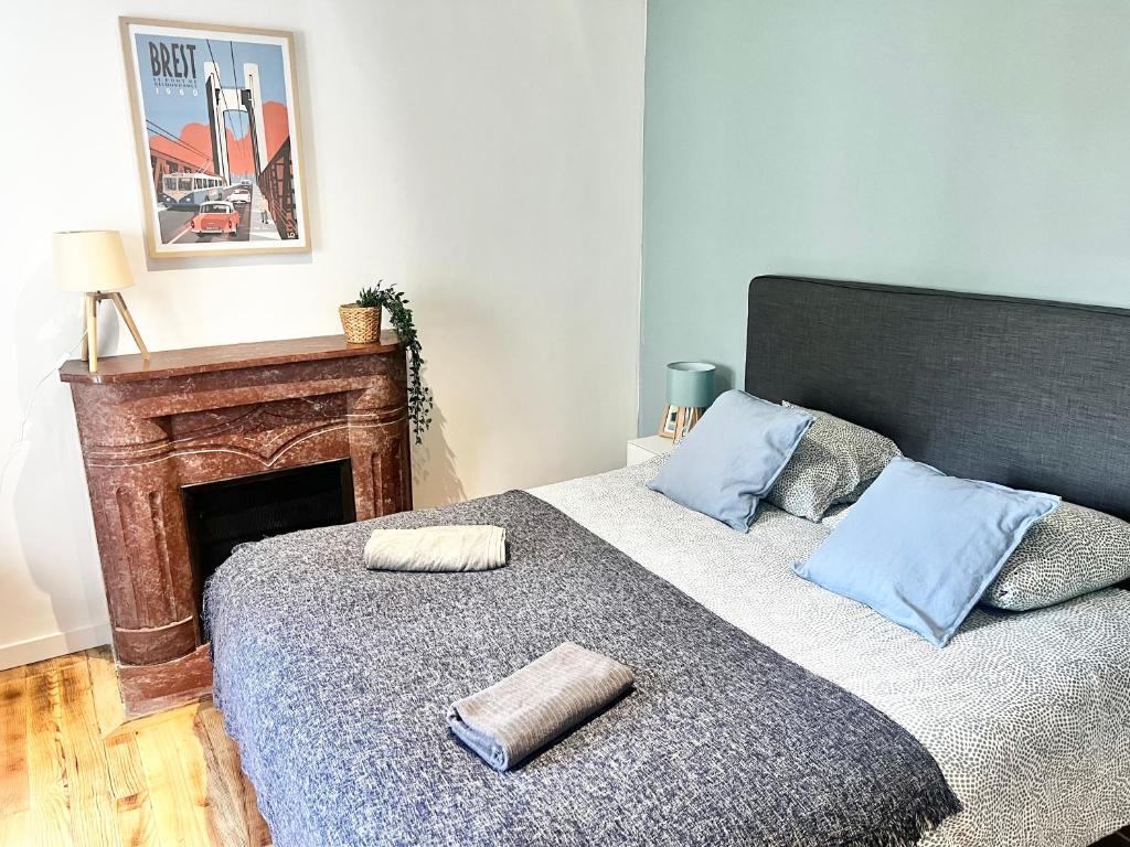 1 dormitorio con 1 cama grande y chimenea en Appartements meublés Brest Saint Marc, en Brest