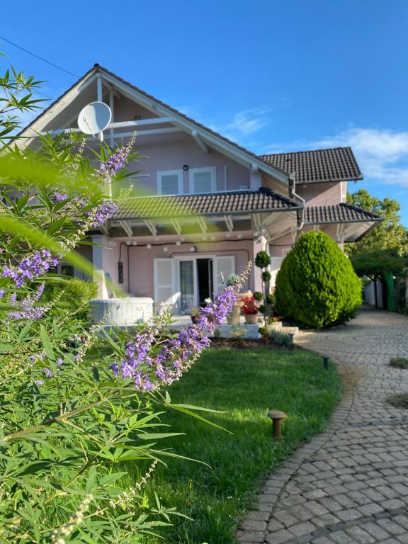 une maison avec des fleurs violettes dans la cour dans l'établissement Villa Scamard, à Zamárdi