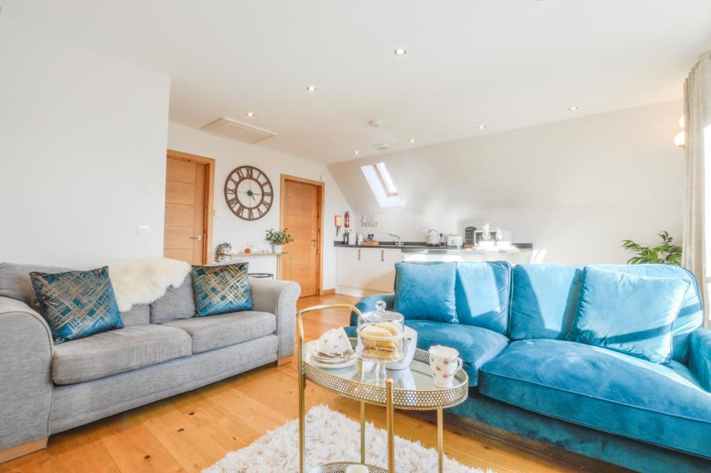 a living room with a blue couch and a table at Rowan Tree Apartment - A modern, quiet hideaway with sweeping views across Oban in Oban