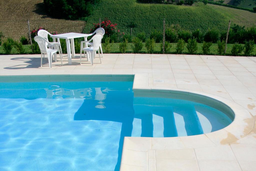 a swimming pool with a table and chairs next to a swimming pool at Agriturismo Fara in Montegiorgio