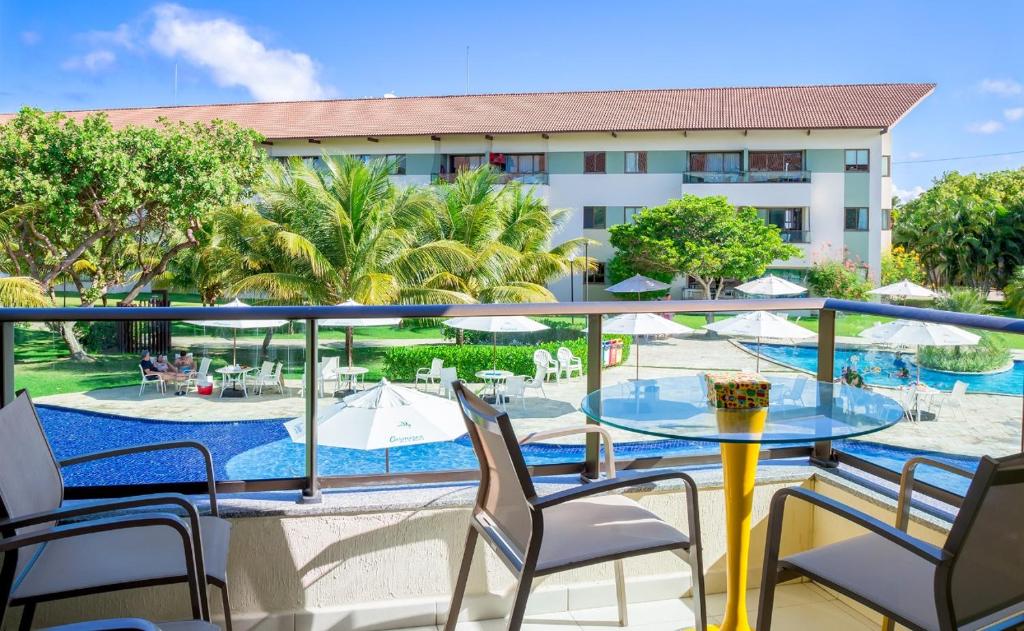 a balcony with a table and chairs and a pool at Paraíso na terra - Carneiros Beach Resort in Tamandaré