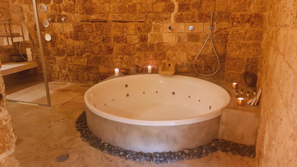 a bath tub in a stone bathroom with candles at Honey suite in ‘Akko