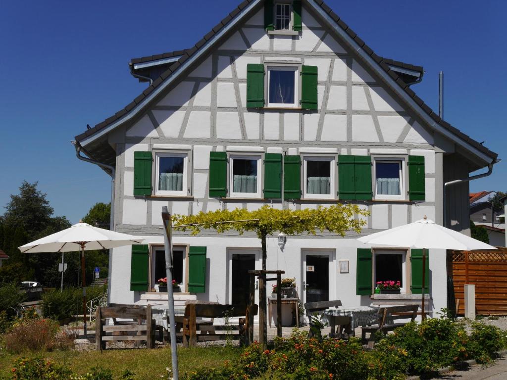 a white and green house with tables and umbrellas at Pension & Café Schlupfwinkel in Salem