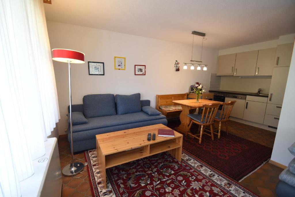 een woonkamer met een blauwe bank en een tafel bij Chalet Christina 7 in Arosa