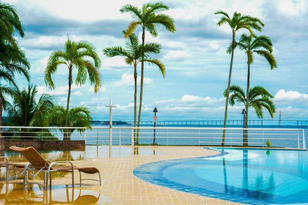 una piscina con palmeras y el océano en Tropical Executive Flat Vista Maravilhosa do Rio, en Manaus
