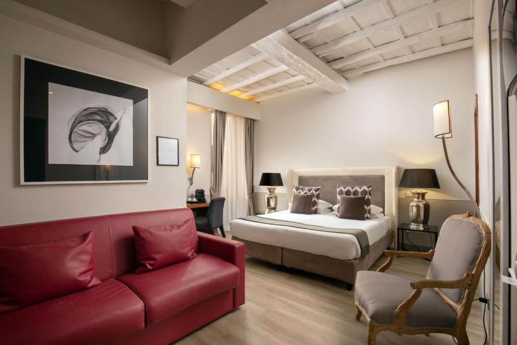 una camera con un letto e un divano rosso di Condotti Palace a Roma