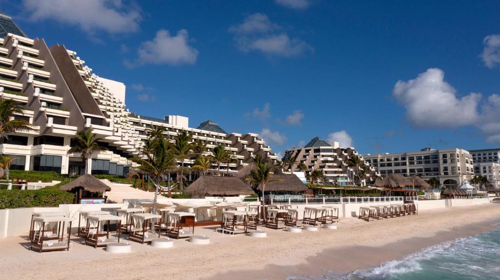 a beach with chairs and tables and a building at Paradisus Cancun All Inclusive in Cancún