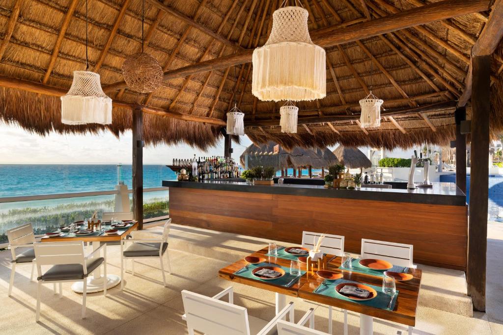 a dining room with a bar and the ocean at Paradisus Cancun All Inclusive in Cancún