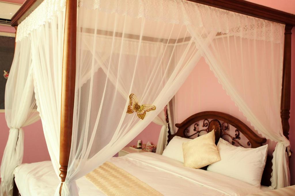 a bedroom with a canopy bed with a butterfly on it at Xinyue B&amp;B in Fenglin