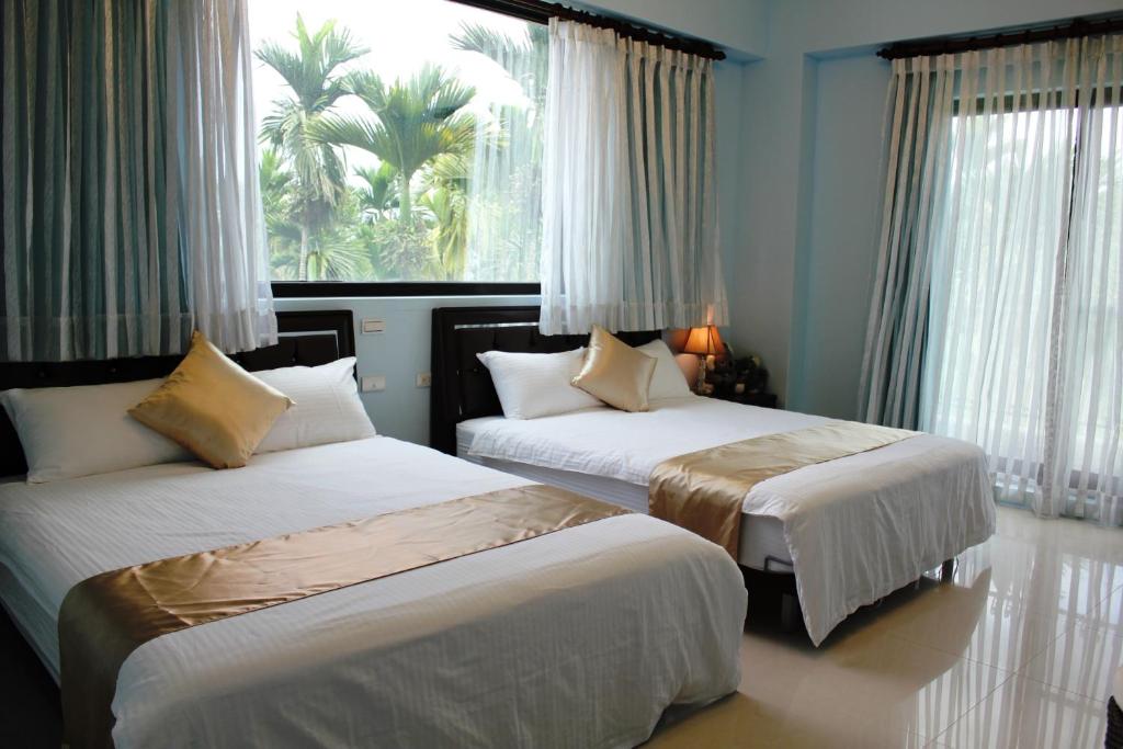 1 dormitorio con 2 camas y una ventana con palmeras en Xinyue B&B, en Fenglin