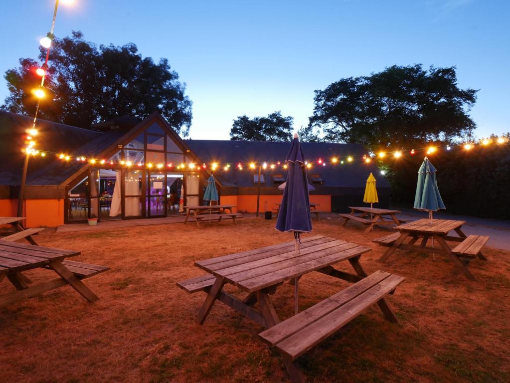 een groep picknicktafels met parasols en verlichting bij ULVF Ty an Diaoul in Sarzeau