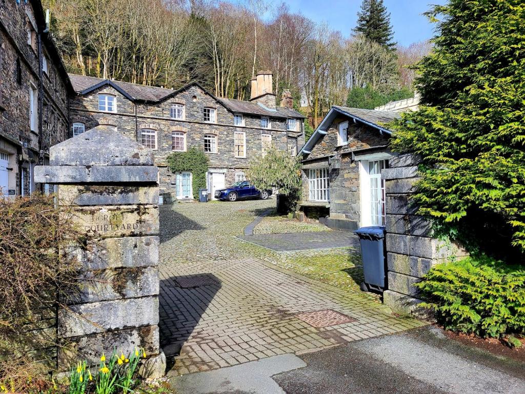 an old stone building with a driveway in front of it at The Old Dairy in Ambleside