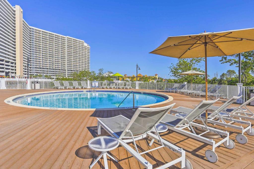 a deck with chairs and an umbrella and a pool at Panama City Beach Living Resort Ideal for Family! in Panama City Beach