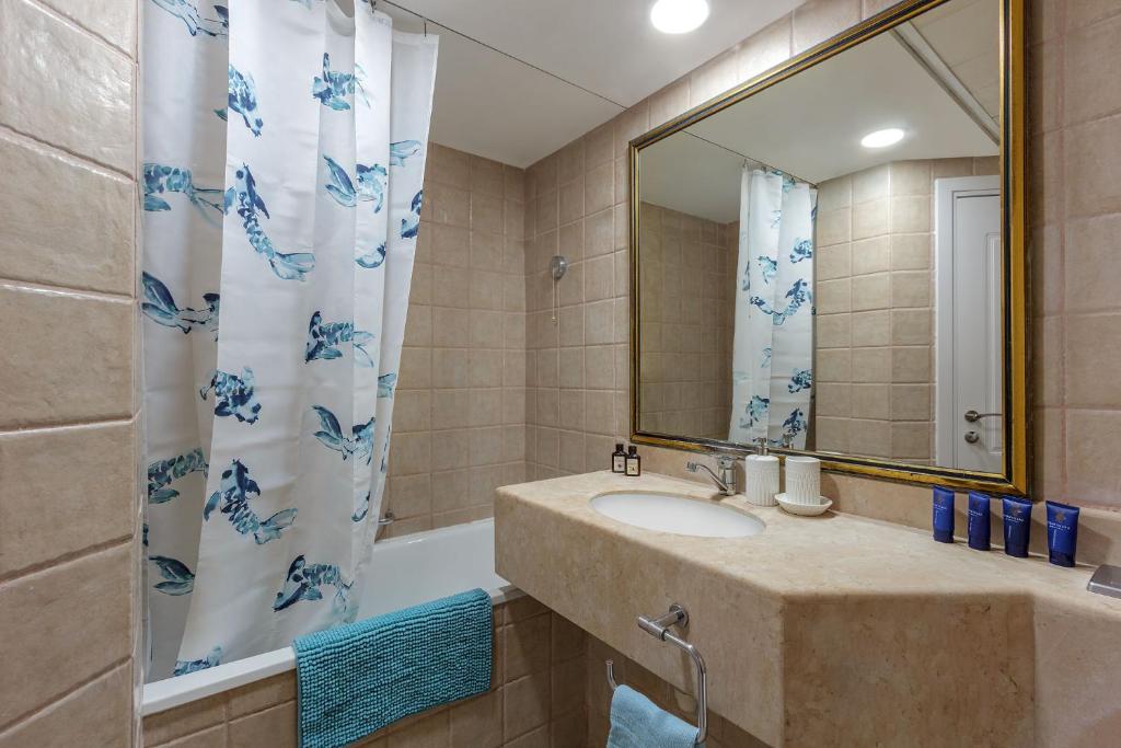 La salle de bains est pourvue d'un lavabo, d'un miroir et d'une baignoire. dans l'établissement Leonardo sea view residence, à Bat Yam