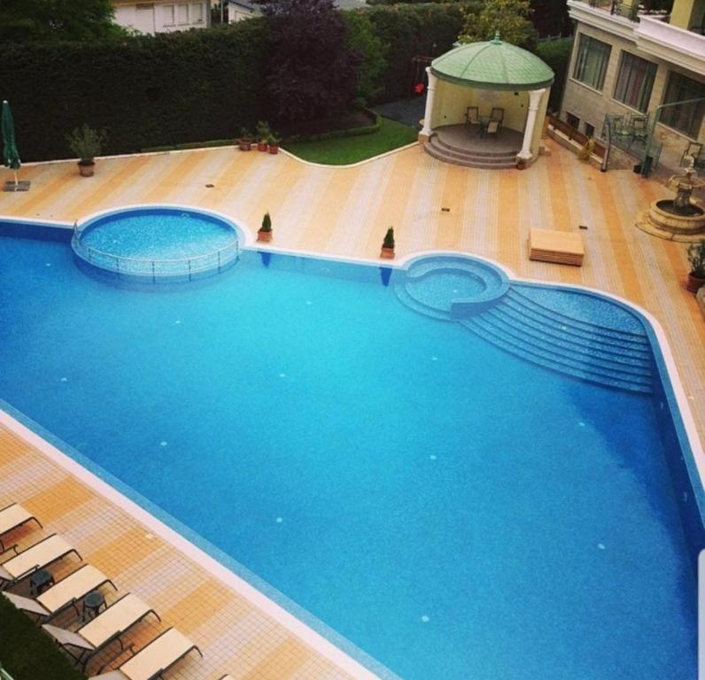 a large blue swimming pool with chairs and a gazebo at Апартаментен Комплекс Сплендид - Студио Афродита, № 113 in Varna City