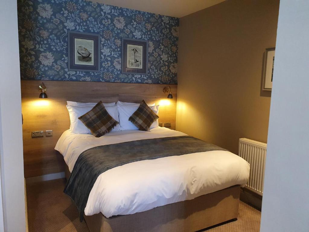 a bedroom with a large bed with blue wallpaper at Old Swan in Skipton