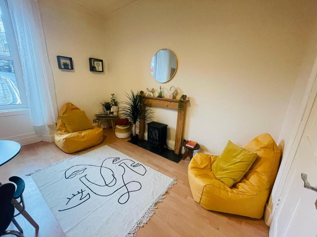 a living room with two yellow chairs and a white rug at Allars Bank Apartment in Hawick