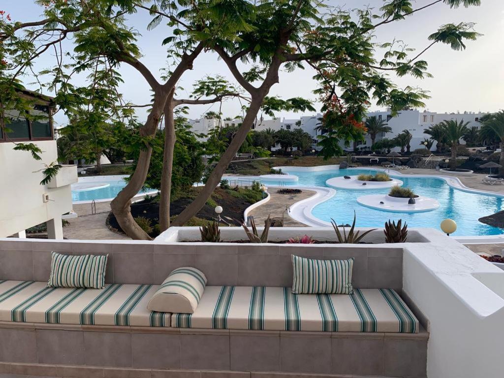un banc en face d'une piscine dans l'établissement Apartamento MIRI, à Costa Teguise