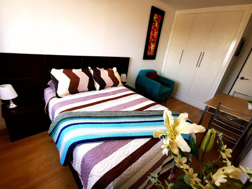 ein Schlafzimmer mit einem Bett und einem blauen Stuhl in der Unterkunft Hab. Privada con la mejor vista in Tacna