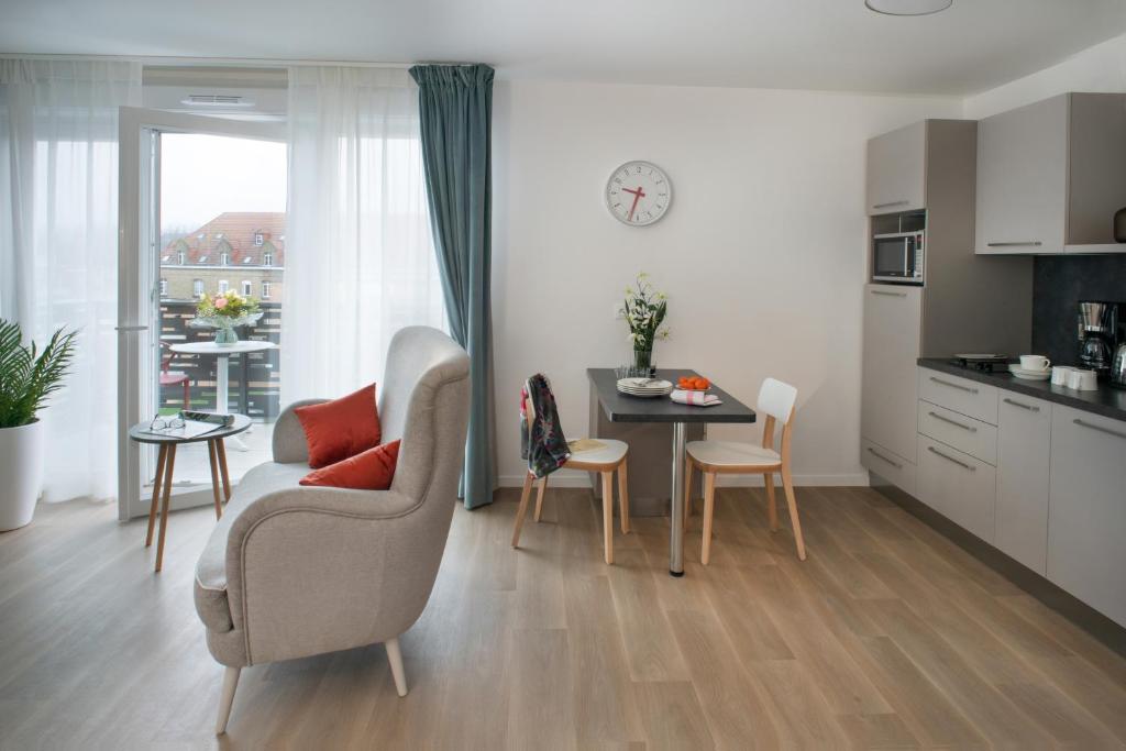 sala de estar con sofá, mesa y cocina en Résidence Services DOMITYS La Cantate, en Dunkerque