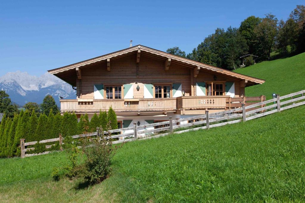 a large wooden house on a hill with a fence at Kitz-Chalet in Kitzbühel