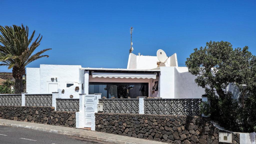 a white house with a stone wall at Casa CHARCO 5 in Charco del Palo